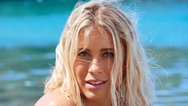 Abby Dahlkemper poses in front of the vibrant green-blue ocean water.